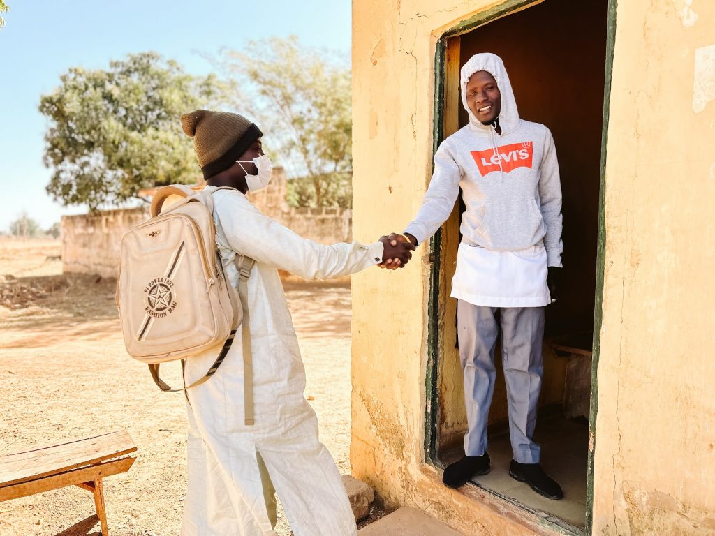 Two men shake hands in the doorway of a house in Kano State, Nigeria.