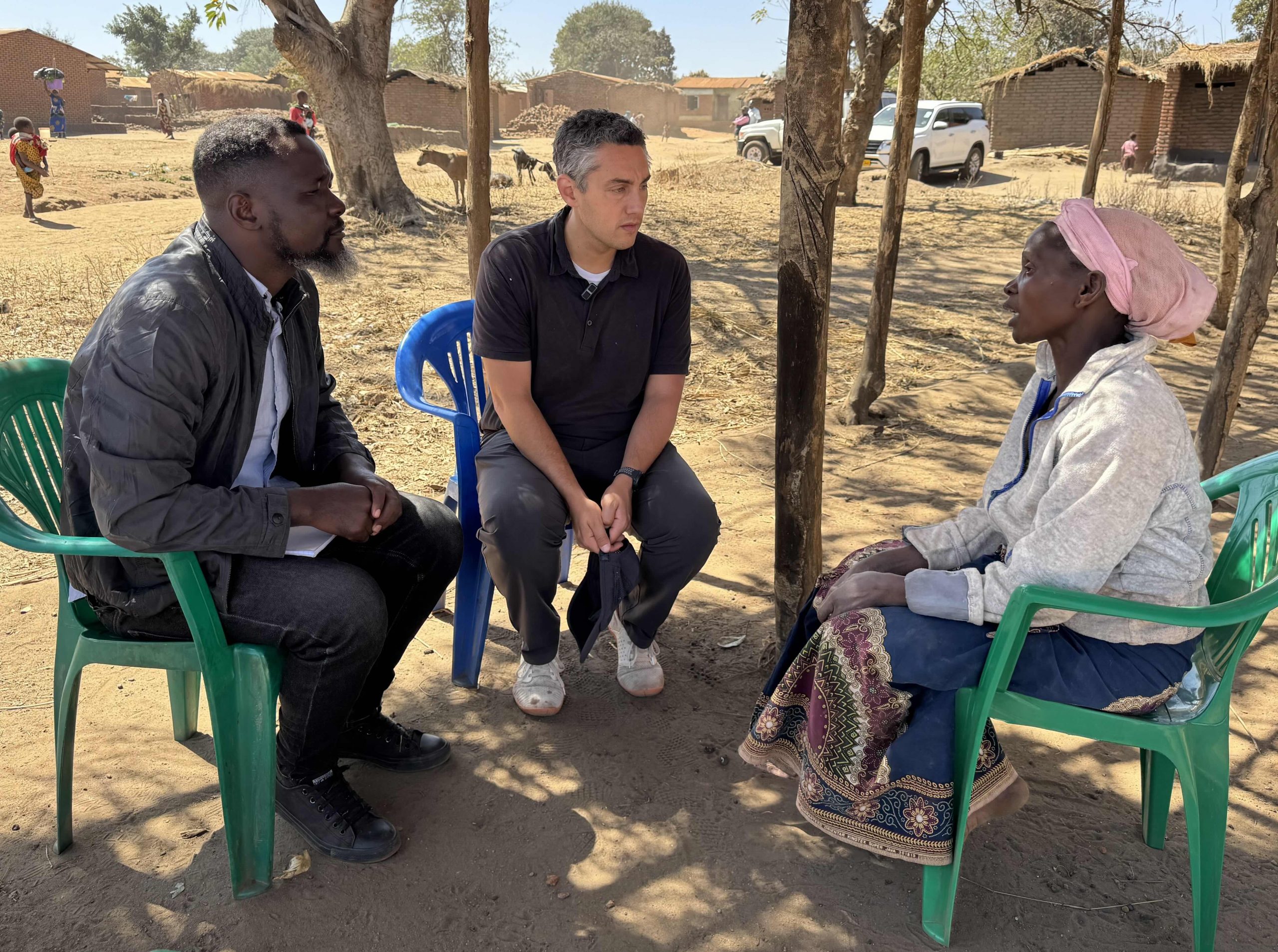 Photo of GiveWell co-founder and CEO Elie Hassenfeld sitting with a translator and a participant of a Spark Microgrants program.