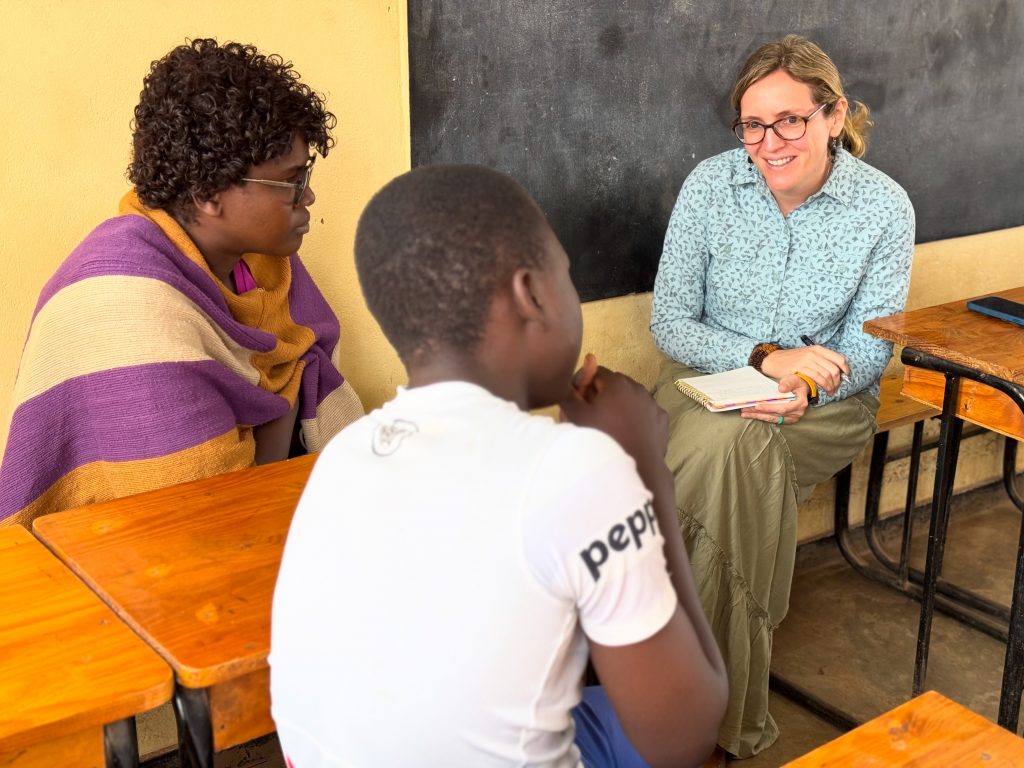 Photo of Senior Program Officer Julie Faller sitting with a translator and a student at a school near the capital city of Lilongwe.
