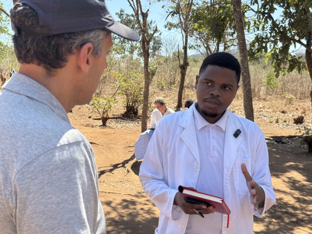 Photo of GiveWell CEO Elie Hassenfeld speaking with a doctor in Malawi.