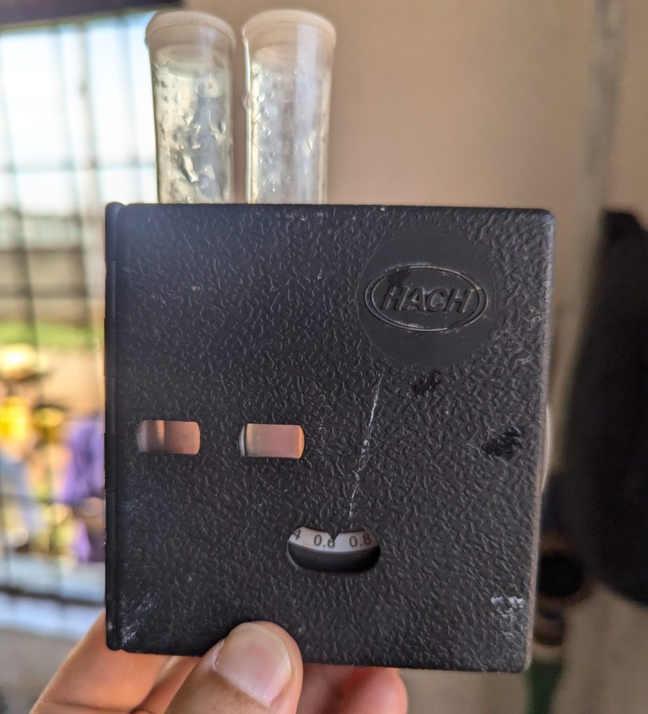 Image of hand holding up water sample with color wheel used to measure chlorine content.